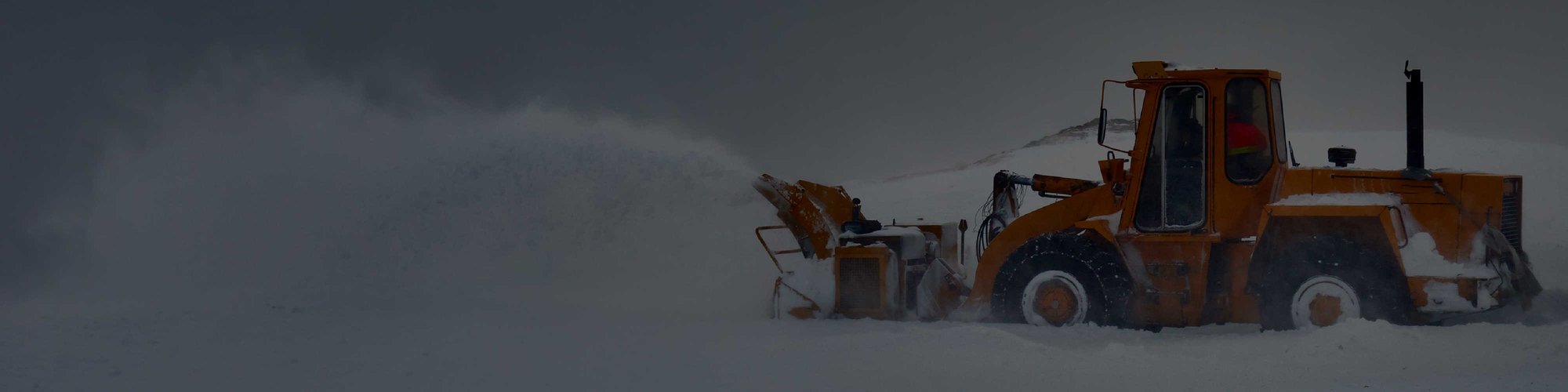 A tractor with a snow plow attachment clearing snow on a hill