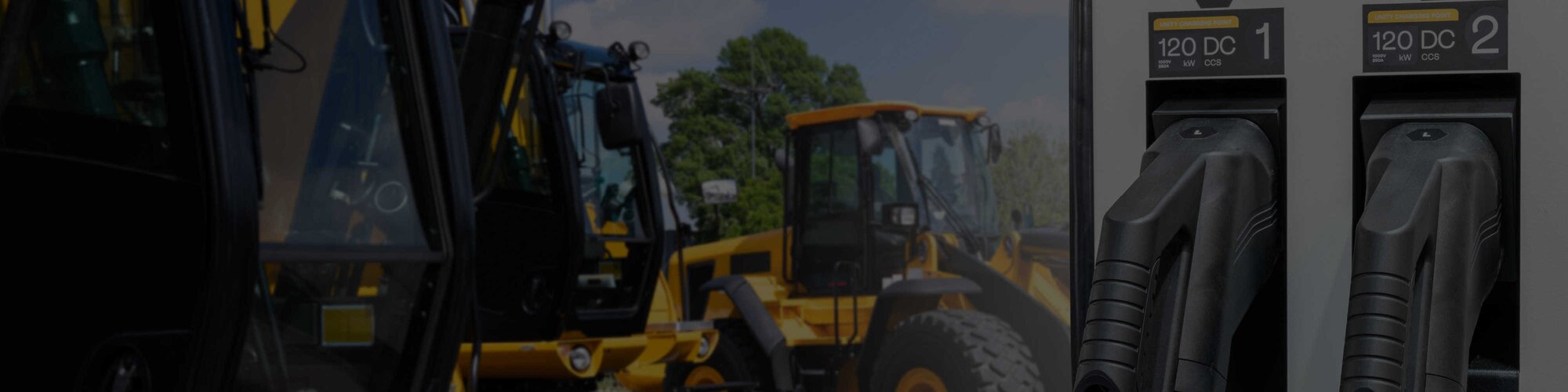 A group of yellow construction machines with an electric charging pump in the foreground