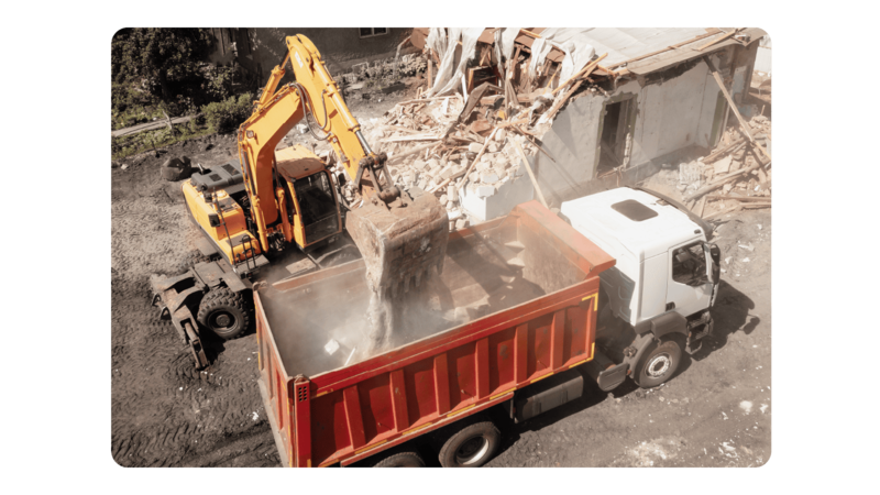 An excavator dumping dirt into a truck