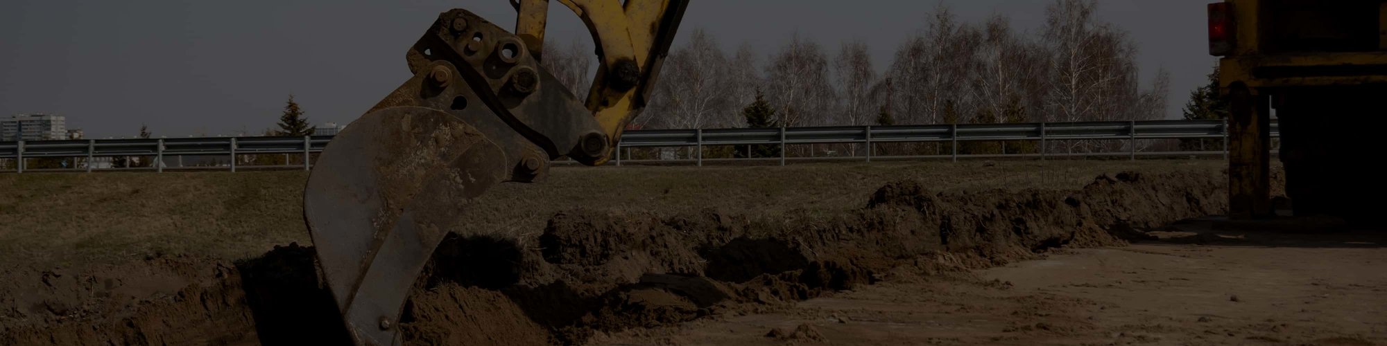 An excavator bucket digging soil on a job site