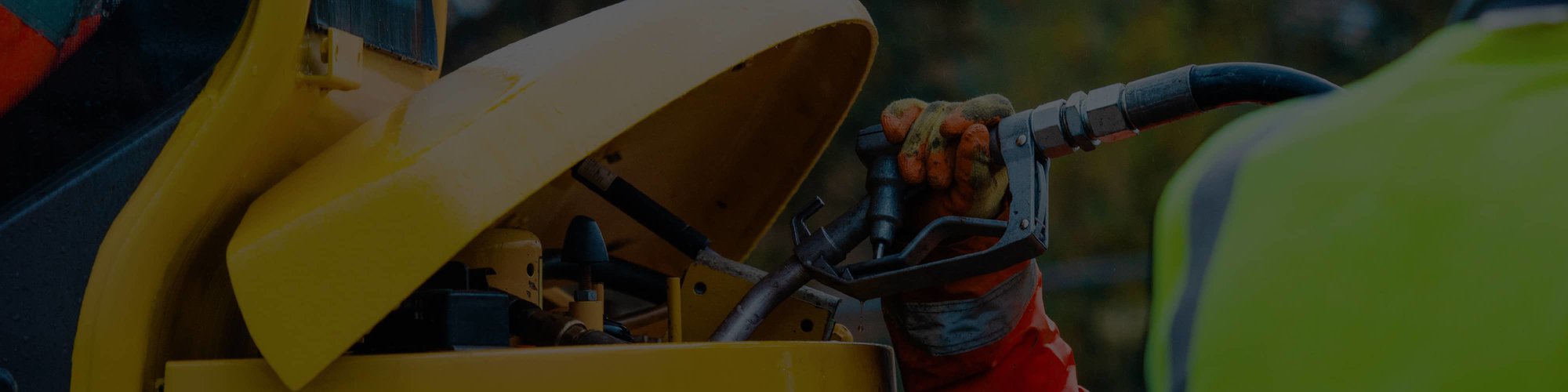 A technician wearing an orange glove and adding fuel to a piece of heavy equipment