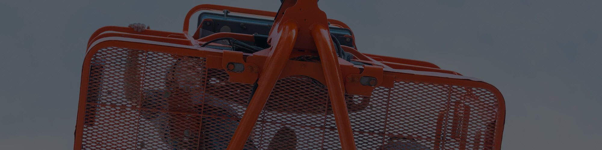 A look up at the platform of a boom lift with a worker standing in it