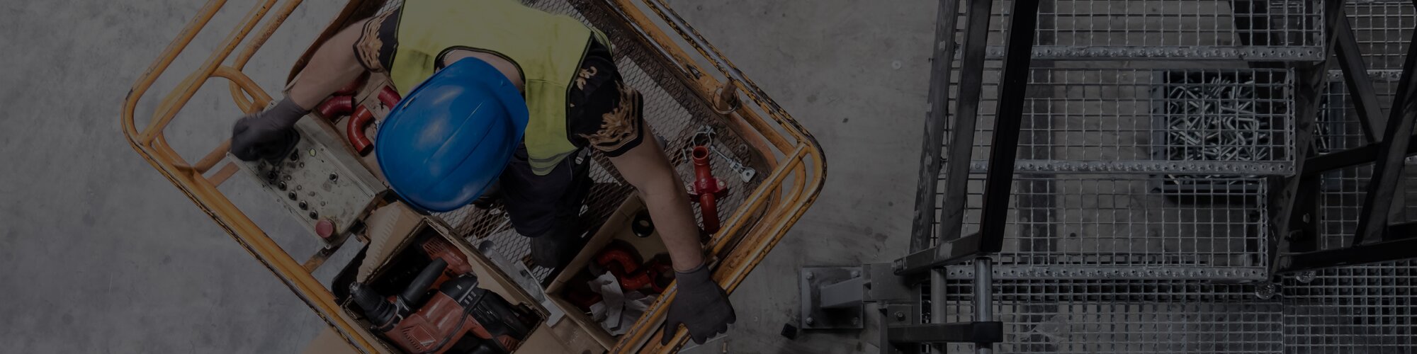 A top-down view of a construction worker on the platform of an electric scissor lift