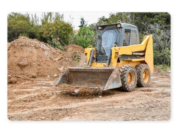 A yellow skid steer with a bucket attachment pushing dirt