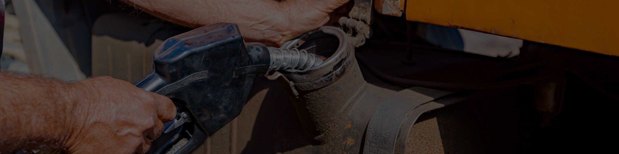 A service tech using a pump to add diesel fuel to an orange machine