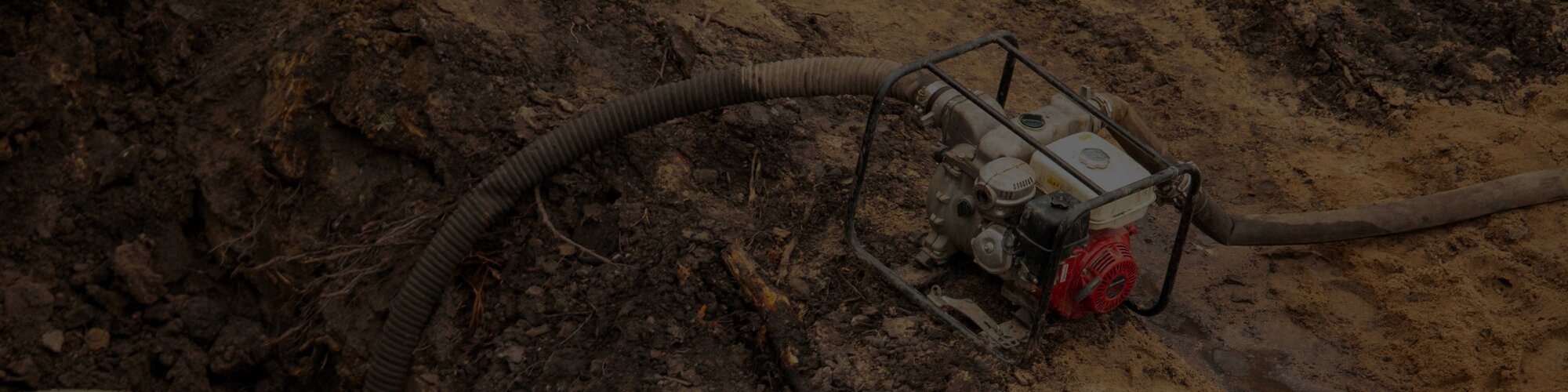 A centrifugal pump sitting on the edge of a hole in the dirt