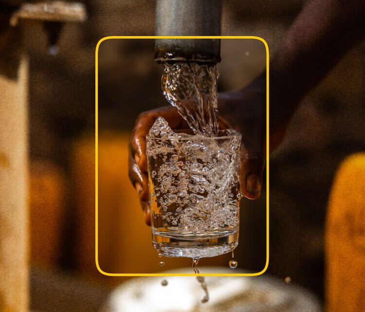 Outstretched hand filling a glass with clean, safe water from a pipe