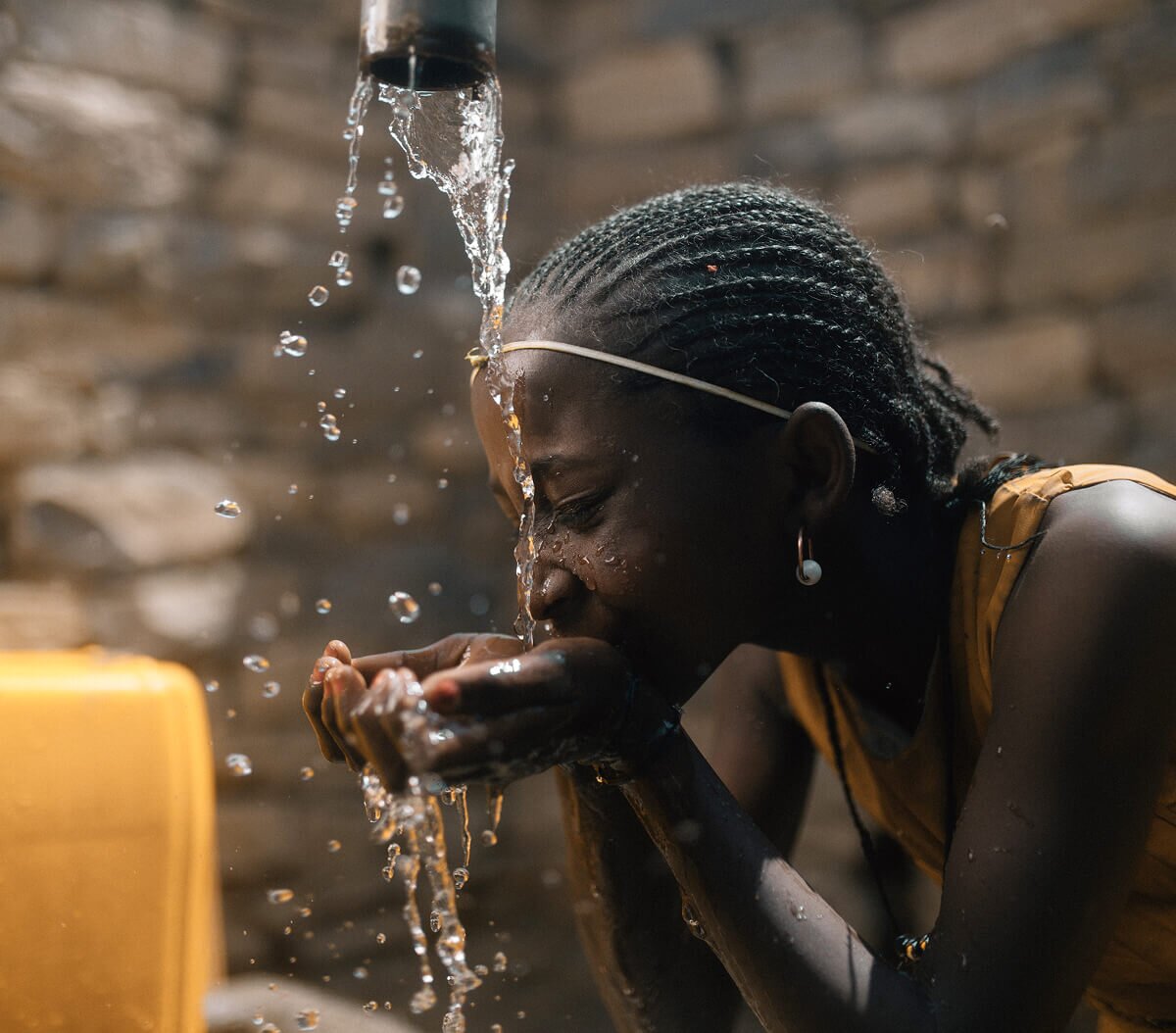 African girl filling her hands with clean, safe water and taking a drink