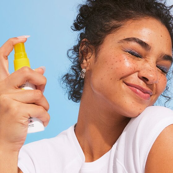 Woman setting her makeup with Suntouchable All Set for Sun SPF 45 Setting Spray