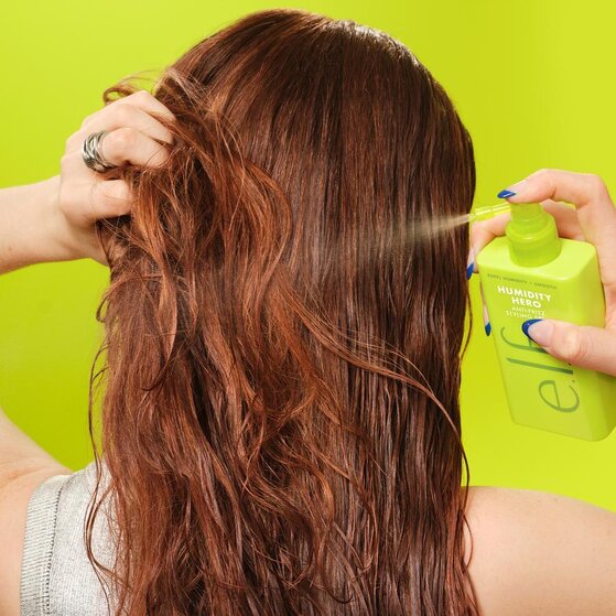 Model with Wavy Hair Applying e.l.f.'s Anti-Frizz Humidity Styling Spray