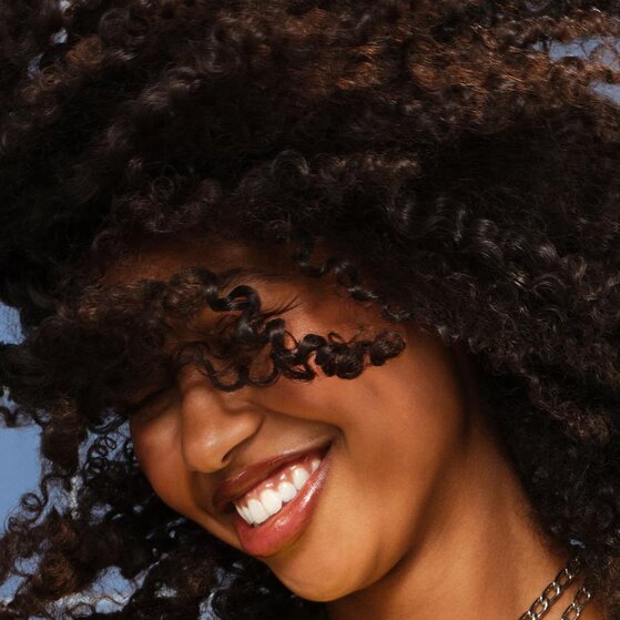 Model smiling after using e.l.f. Never Thirsty Shampoo and Conditioner