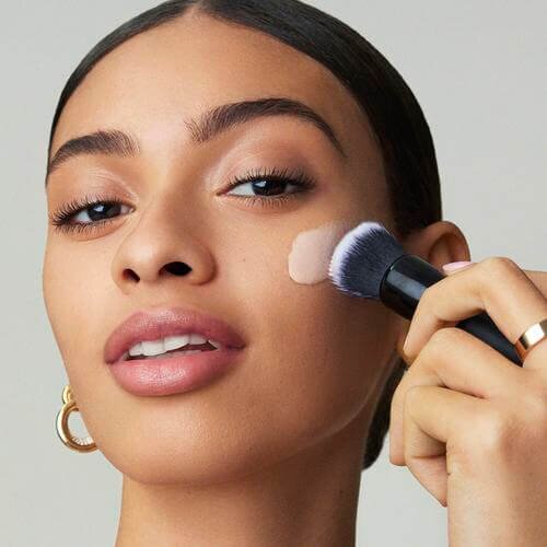 Model applying e.l.f. Liquid Poreless Putty Primer with Putty Primer Brush and Applicator