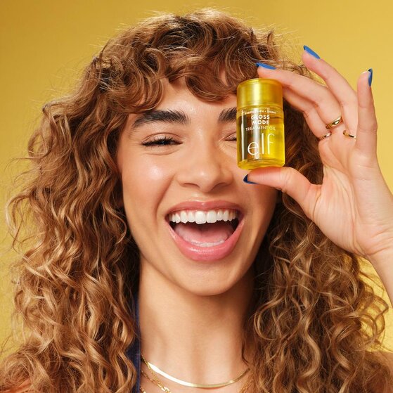 Model with Curly Hair Holding e.l.f.'s Hair Oil for Shine