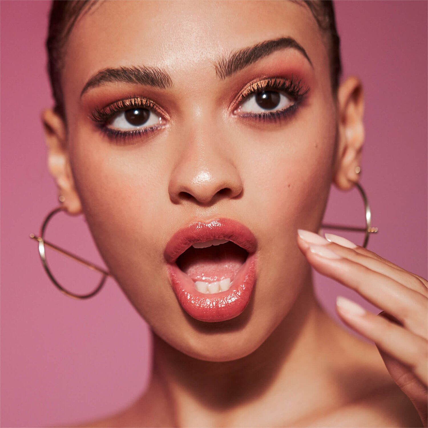 Woman with red lipstick holding silver hoop earrings