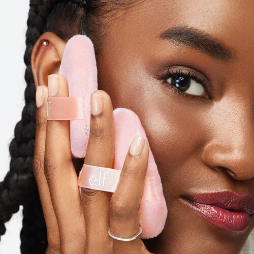Someone using e.l.f. Halo Glow Powder Puffs on right cheek.