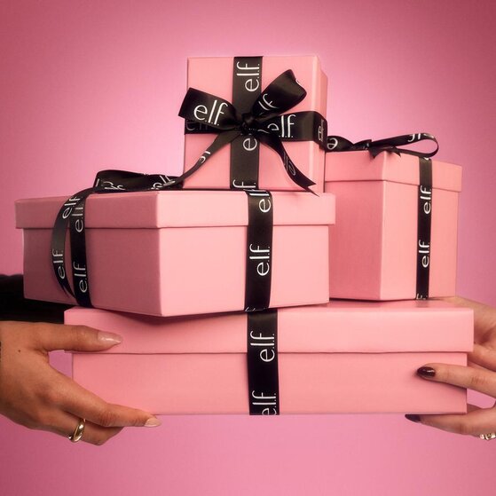 Hands holding pink holiday gift boxes with black ribbon