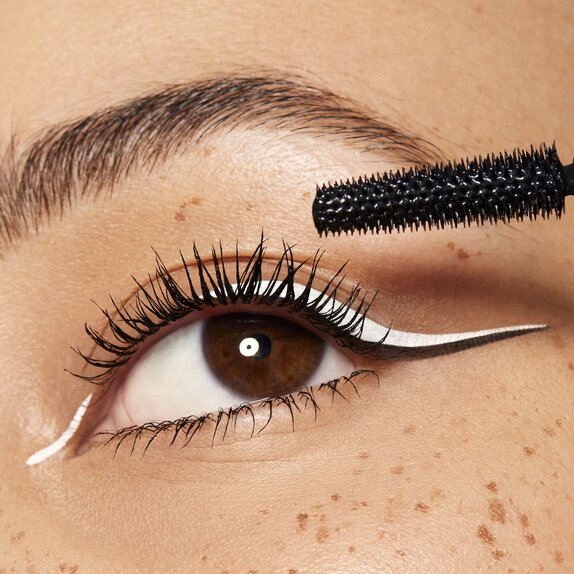 Woman applying mascara with white eyeliner