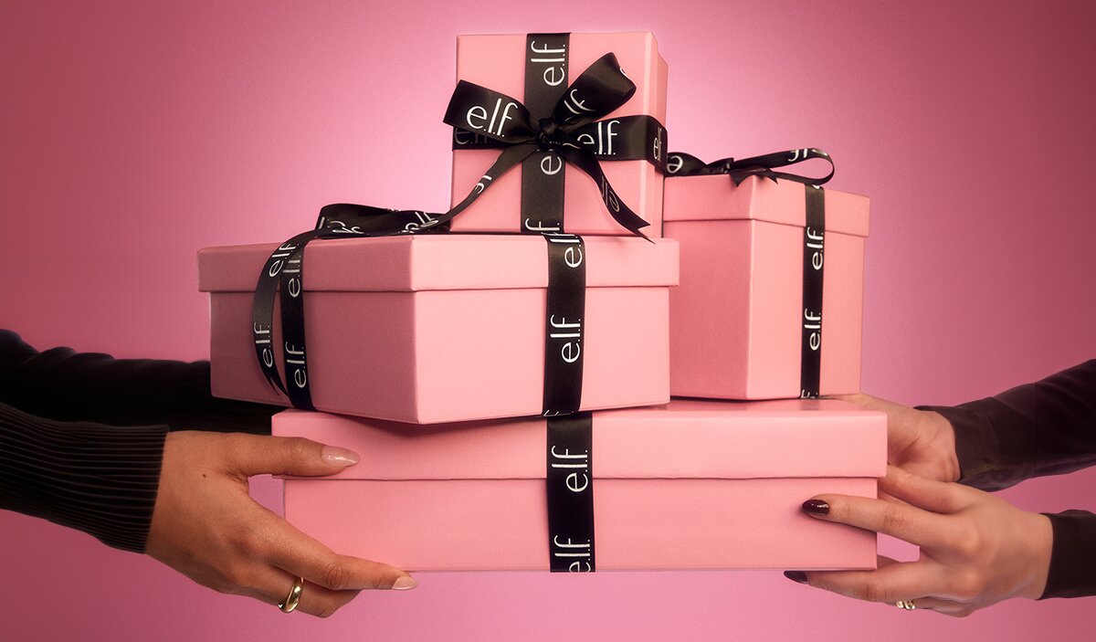 Hands holding pink gift boxes with black ribbon