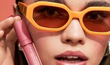 Someone with sunglasses holding e.l.f. Sun Boss Gloss SPF 25
