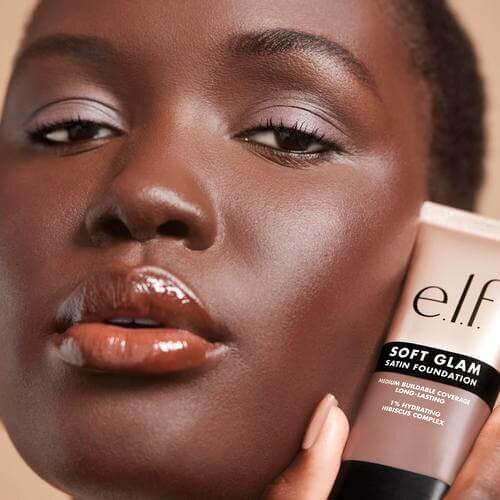 Woman holding and wearing Soft Glam Satin Foundation