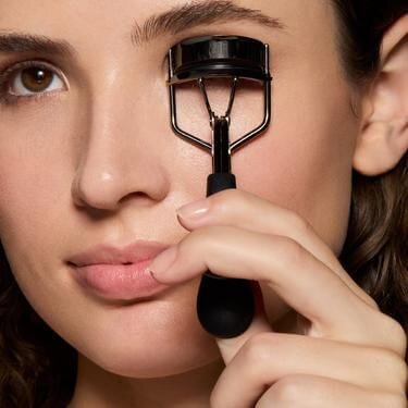 Woman using an eyelash curler to curl lashes