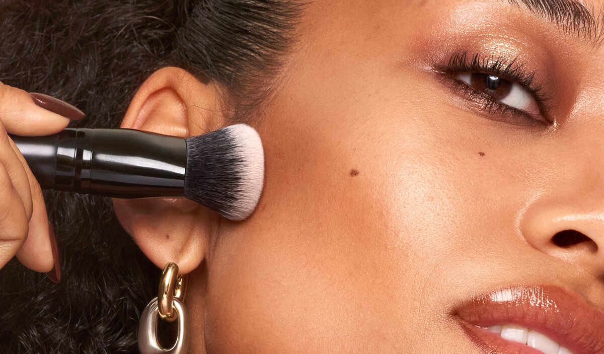 Model applying liquid bronzer with bronzer brush