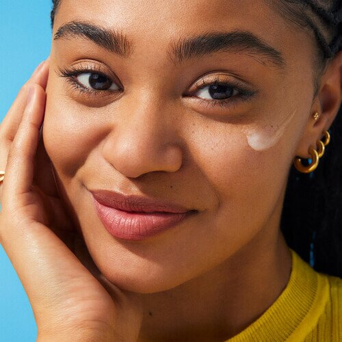 Model applying clear sunscreen to face