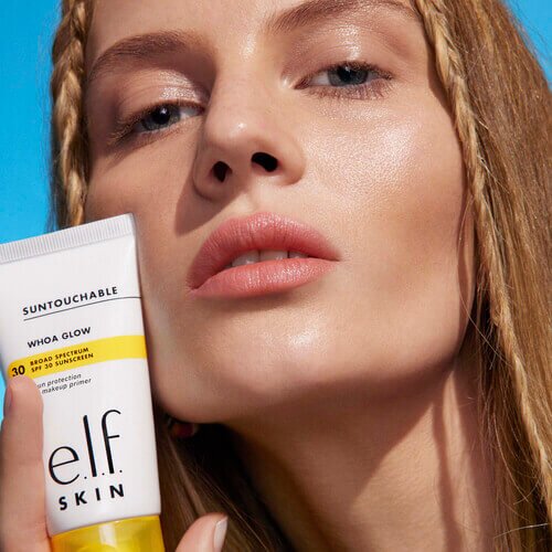 Woman holding Suntouchable Whoa Glow SPF 30 - Face sunscreen and makeup primer hybrid