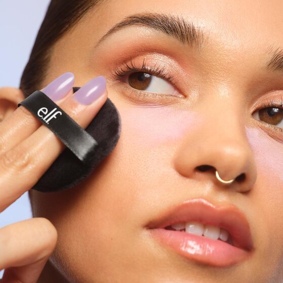 Model applying lavender setting powder to under-eye area