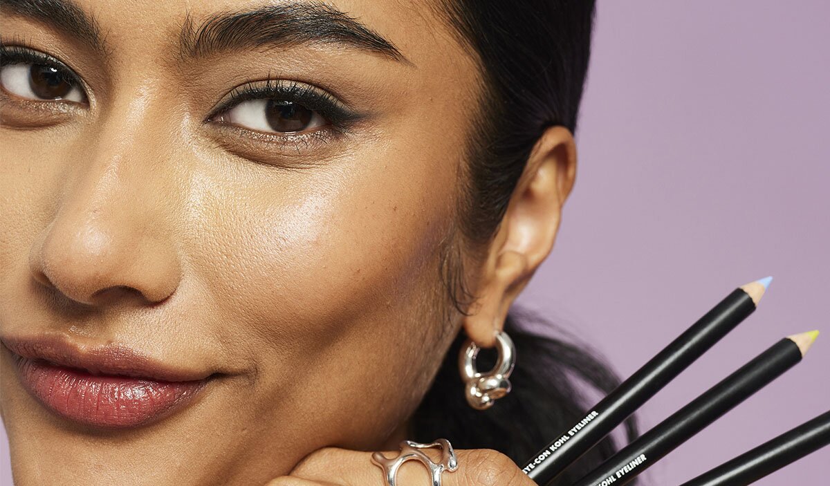 Model with a smokey eye look holding three kohl eyeliner pencils