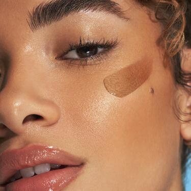Model applying bronzing serum to skin