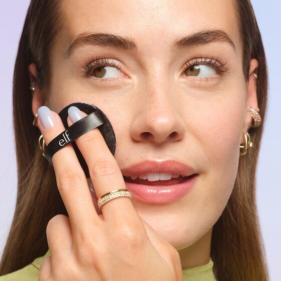 Model using powder puff to apply loose face powder