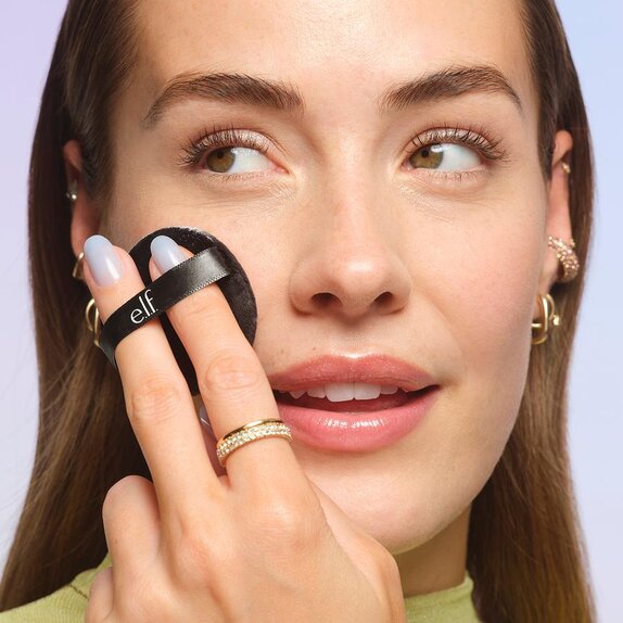 Model using powder puff to apply loose face powder