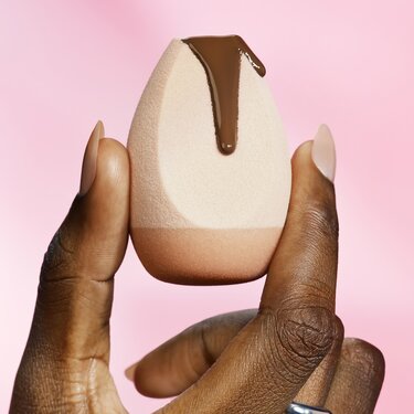 Model holding makeup sponge with halo glow skin tint on the sponge