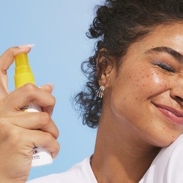 Model spraying SPF mist to face