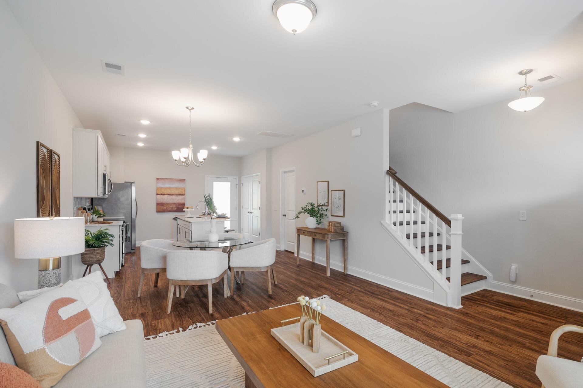 Open-concept townhome interior at Pinewind at Liberty Hall featuring modern kitchen, dining area, and hardwood-style floors.