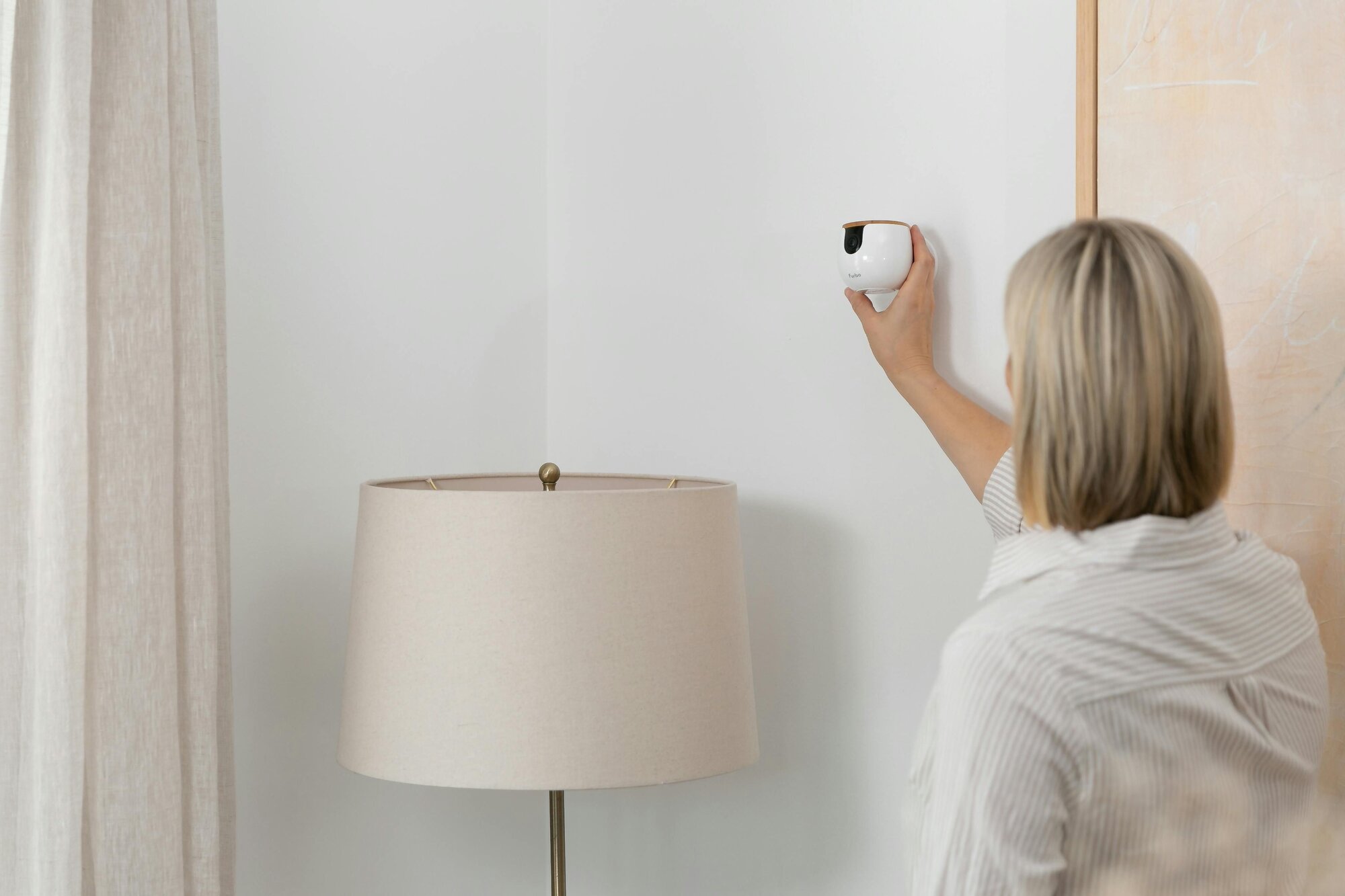 Woman setting up wall-mounted Furbo Mini 