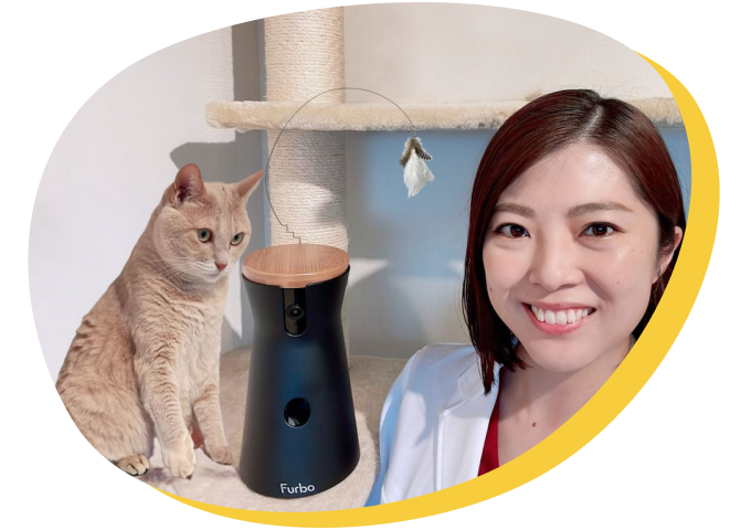 A veterinarian smiling beside a Furbo cat camera and a cat.