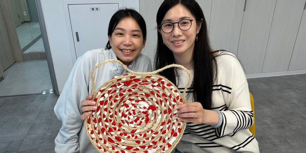Two women holding a handmade cat scratcher