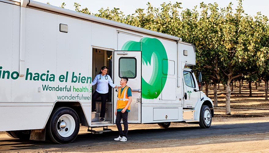 A provider stands outside a mobile clinic with an employee