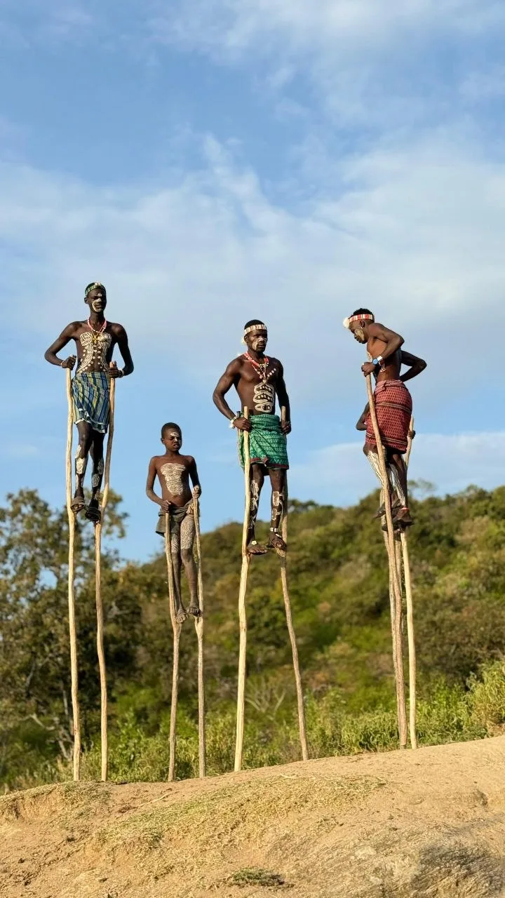 Travelers and community members gathered beside thatched homes in Ethiopia