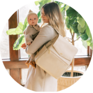 Mother holding baby while wearing the Freshly Picked Diaper Bag II