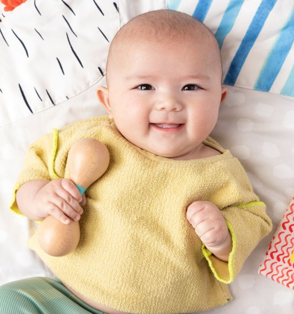 Baby holding Lovevery rattle