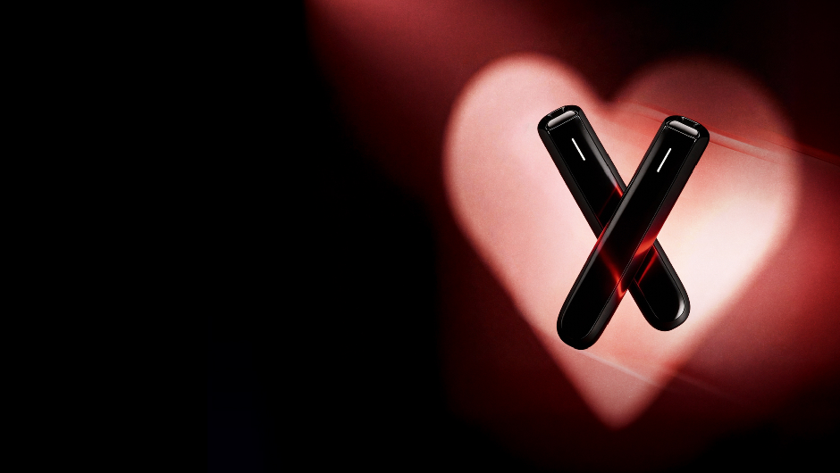 2 zariadenia Ploom AURA v čiernej farbe Jet Black na valentínskom pozadí so srdcom