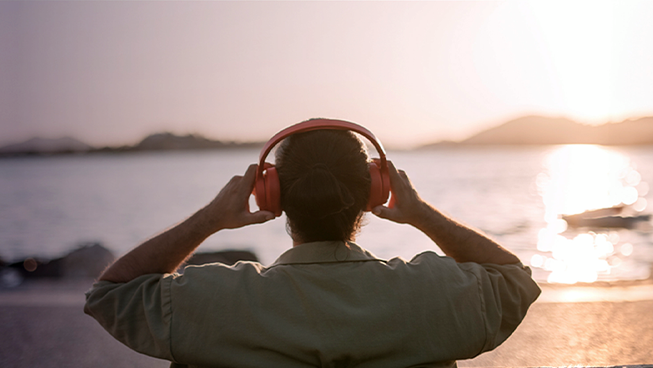 Muž so slúchadlami na hlave počúvajúcu hudbu pri vode