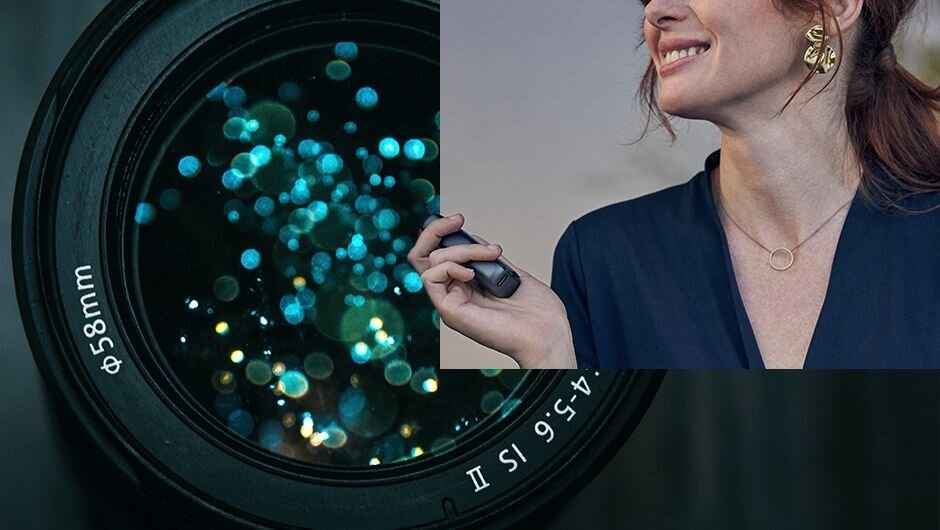 Detailný záber na objektív kamery a ženu, ktorá drží v ruke zariadenie ploom x