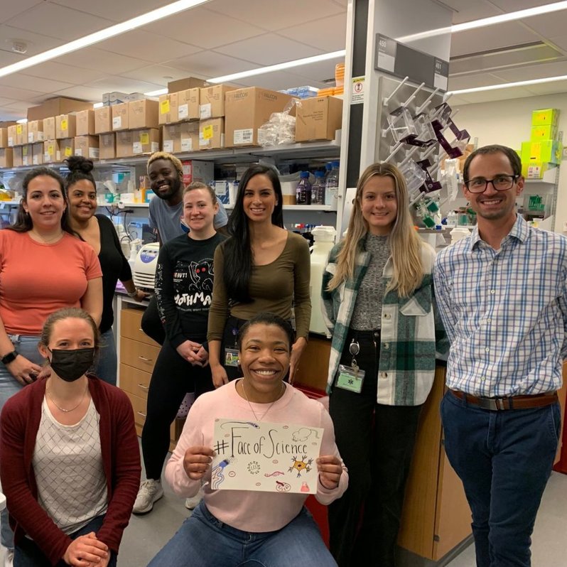 9 researchers in the @kelliejurado  lab posing for a photo with a #FaceOfScience sign