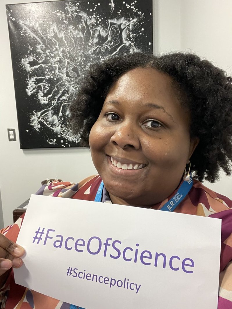 Raechel McKinley, Ph.D. holding a sign with #FaceOfScience