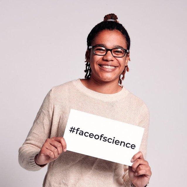 Ayanna Culmer-Gilber smiling and holding a sign that reads #FaceOfScience