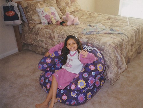 A young Cecilia Hinojosa sitting on an inflatable Barbie chair.